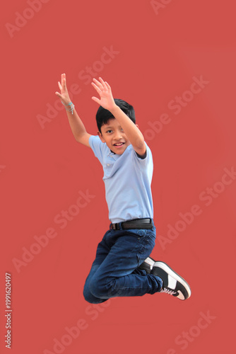 9-year-old Latino boy with dark skin jumps for joy to celebrate his excitement