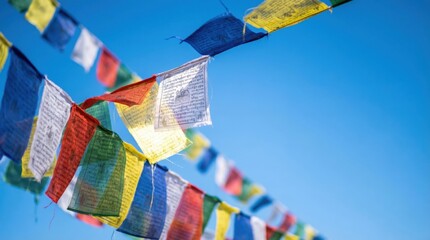 Colorful Tibetan prayer flags fluttering in the wind against a bright blue sky
