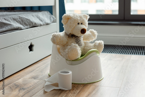 A toy bear sits on a baby potty in a room, the concept of potty training a child Toilet training concept.