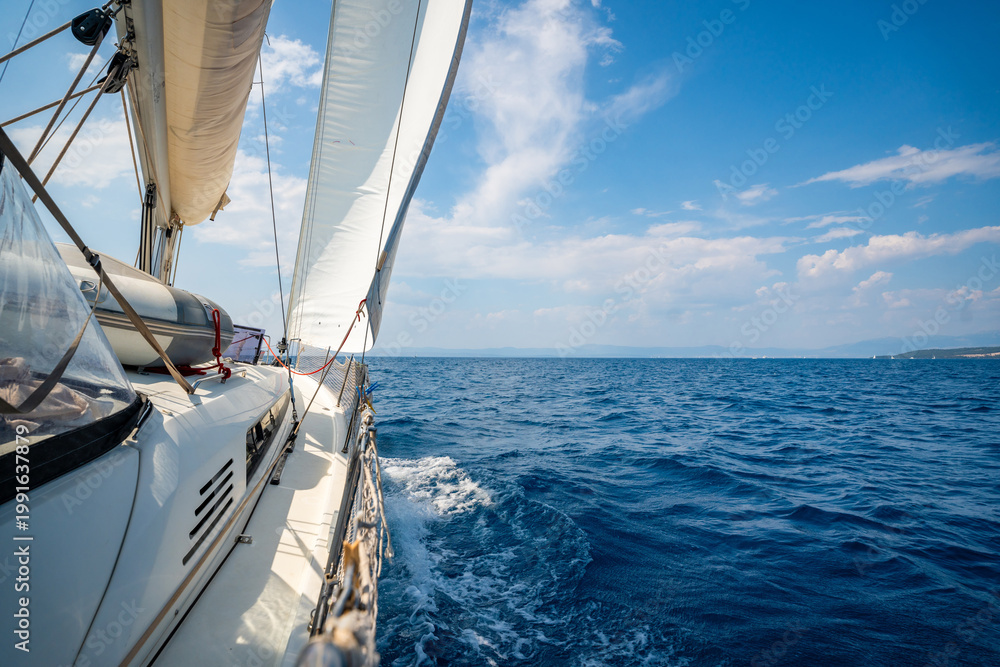 Fototapeta premium Side of a sailing yacht cutting through the sea with full sails near Croatia. Motion, freedom, sailing lifestyle and adventure on the open water.