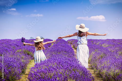 Photos A happy mother and her daughter in white dresses walking over a lavender field i