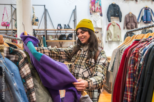 Quadro em tela Young woman finding vintage clothes in a thrift store