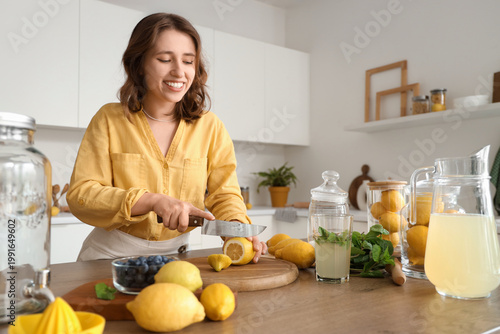 Young woman cutting lemon f...