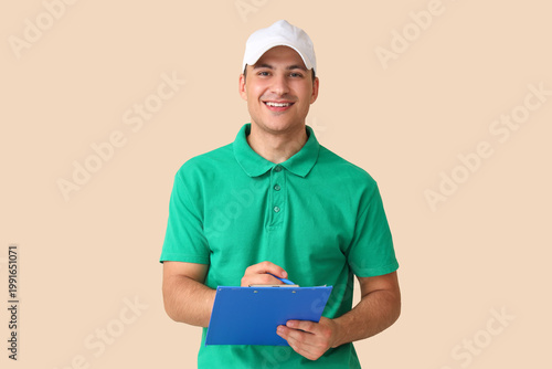 Delivery man writing in clipboard on beige background