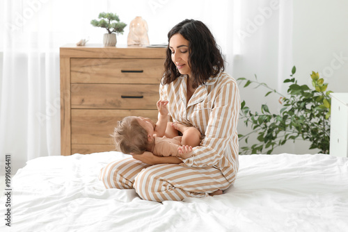 Fotografía Happy mother with her little baby sitting on bed at home