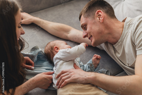 Happy parents bonding with their adorable baby on a comfortable sofa at home