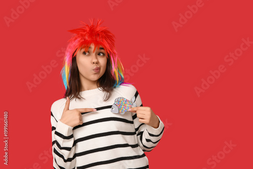 Beautiful young thoughtful woman in funny disguise pointing at paper fish on ...