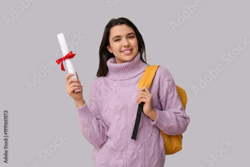 Happy smiling female student with backpack and diploma on white background