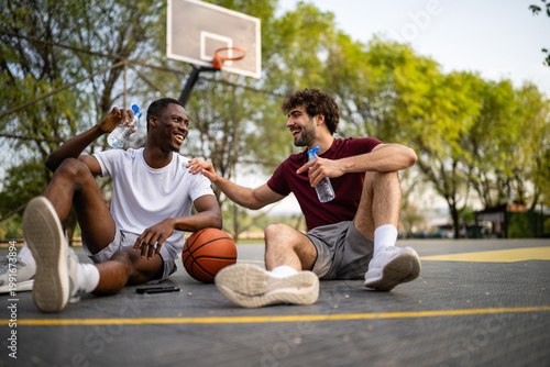 Fotografía Diverse men friends resting talking on basketball court