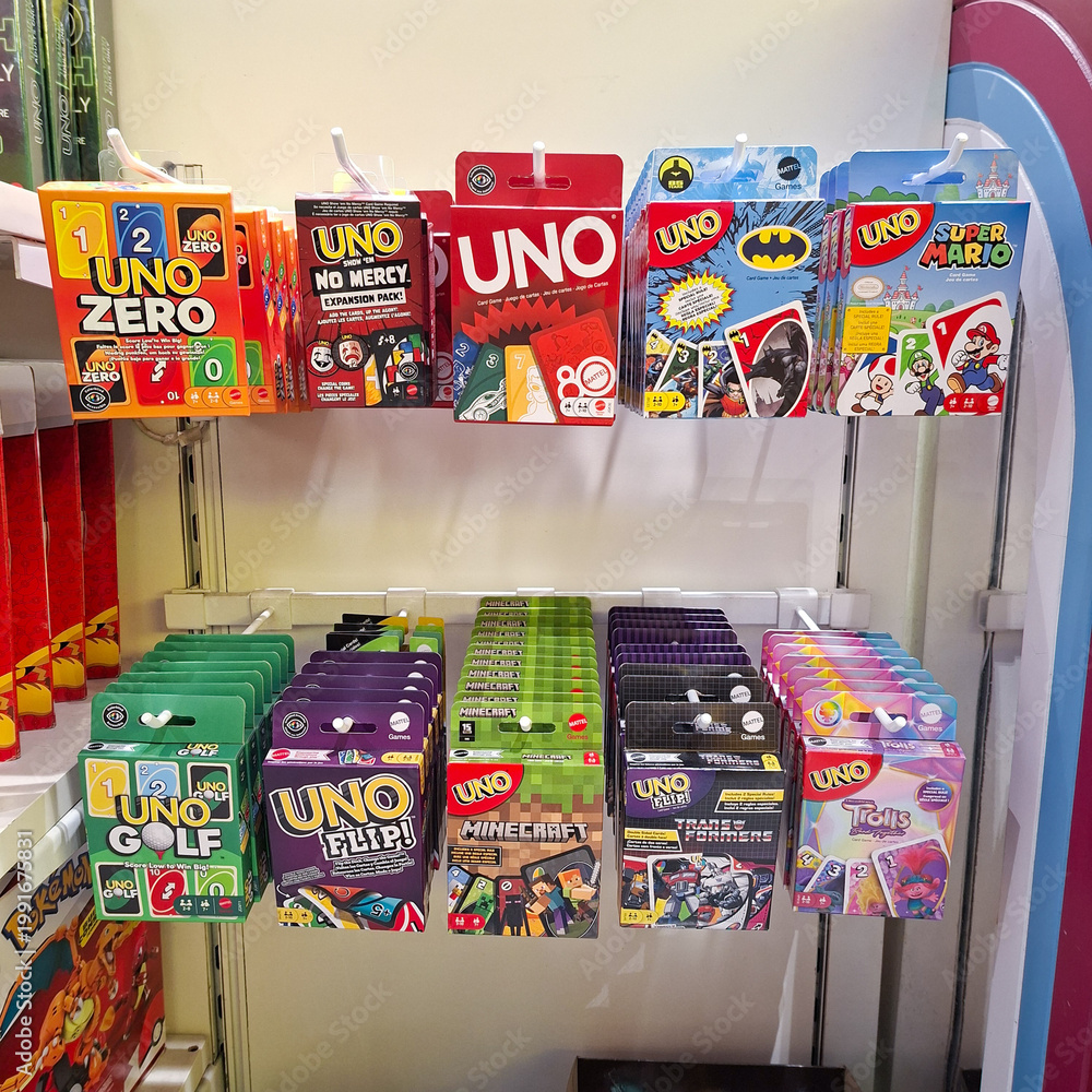 Naklejka premium Assorted UNO card game decks on display at a retail store shelf featuring various themed editions and popular family card game packaging on April 19, 2026 in Bangkok, Thailand.