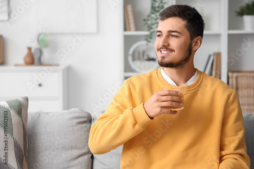 Young man with glass of juice at home