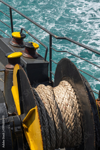 Quadro su tela A heavy-duty marine winch with a thick rope is mounted on a ship deck, with the open sea in the background, symbolizing maritime work, transport, and nautical operations