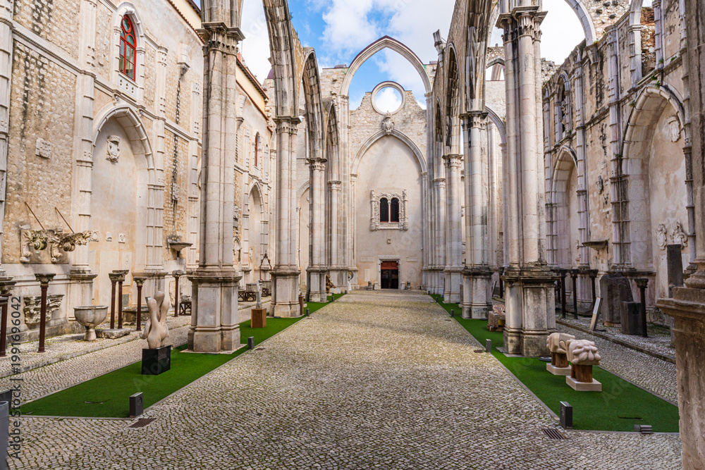 Fototapeta premium Historic ruins of Carmo Convent in Lisbon featuring gothic arches, stone columns and open roof courtyard, showcasing medieval architecture and cultural heritage in Portugal.