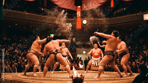 Sumo wrestlers performing a salt-throwing ritual in a crowded arena with a dramatic atmosphere.