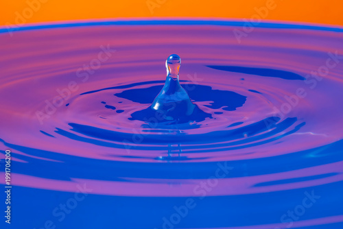 The bounce of a drop on a surface of colorful water with specular reflections