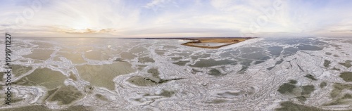 Aerial view of a mosaic of ice floes and ice shove on frozen waters of lake Markermeer in winter along the coast of Noord-Holland with nature reserve De Neck, in 360 degrees panorama, Netherlands.