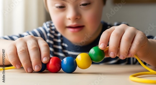 Child with Down syndrome playing with colorful wooden beads on string. Educational activity for sensory development and fine motor skill practice. Inclusive learning and childhood.
