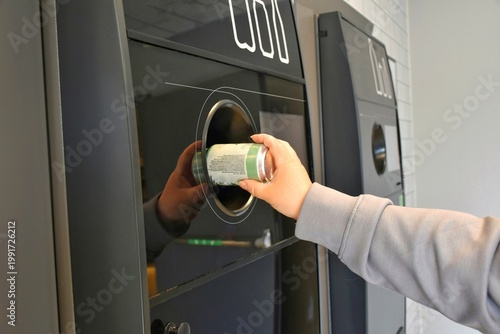 Fotografie Returning empty cans to a supermarket recycling machine to reduce waste and reuse aluminum