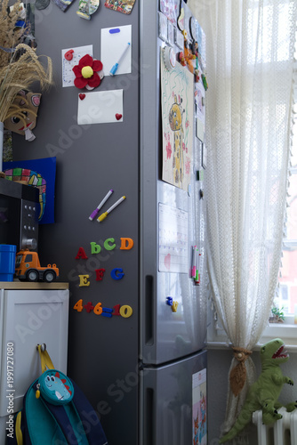 Modern Fridge with Colorful Magnets, Kid's Drawings and Alphabet Letters