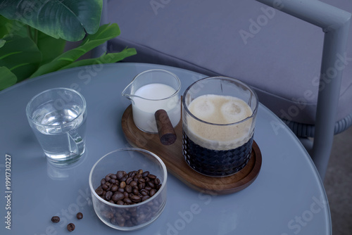 Black Coffee with Crema, Milk Pitcher, and Coffee Beans on Gray Table