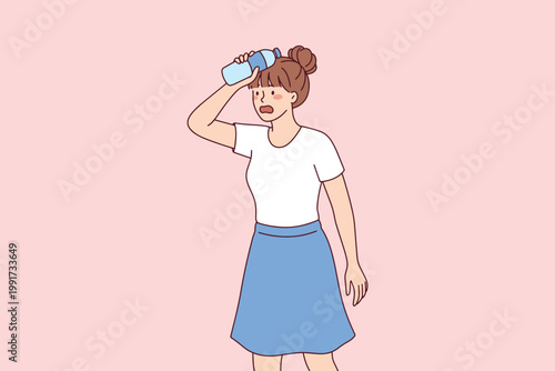 Young woman with water bottle suffering from heatstroke or dehydration on a hot summer day. Shading eyes from bright sunlight outdoors.