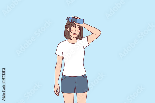 Tired woman cooling herself down with a water bottle against her forehead. Concept of heat exhaustion, dehydration, and staying cool during summer.