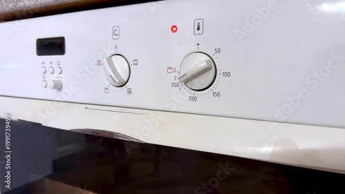 Close Up White Oven Control Panel Knob Turning To Preheat Red Indicator Light Glowing Numeric Temperature Dial