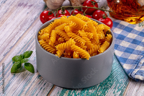 Foto Fusilli Pasta Bowl with Fresh Cherry Tomatoes, Garlic, Basil, Rustic Wood Backgr