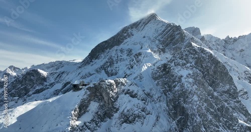 Aerial view of the snow-covered Zugspitze mountain peak, a majestic building clings to the mountainside, Garmisch-Partenkirchen, Bavaria, Germany.