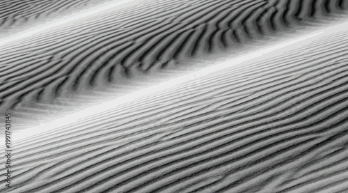 Abstract black and white texture of sand dunes with rippled patterns and high contrast shadows, creating a minimalist desert landscape