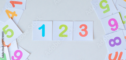 Numbers 1, 2, 3 on colorful flashcards in the center of white background.  Flat lay composition of bright number cards counting from one to three. Surrounded by scattered cards, this image represents 