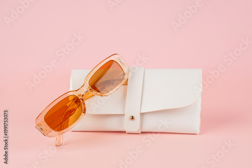 Sunglasses, fashion eyewear, and a glasses case against a pink background.