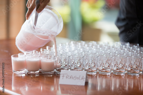 Mano che regge una caraffa e versa sorbetto tosa in bicchieri