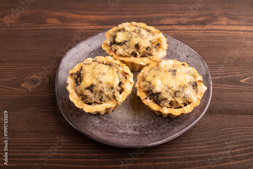 Tartlets with meat and cheese on brown wooden. side view, close up