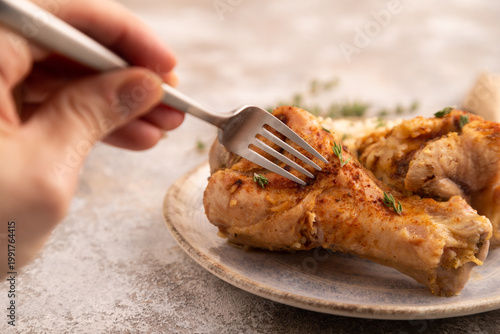 Fried Turkey Wing with spices and rice with hand on brown concrete, side view, close up, selective focus