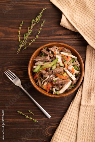 Meat salad with beef and vegetables on brown wooden, top view, close up