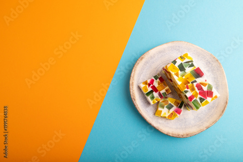 Colored Fruit and milk jelly on blue and orange paper, top view, copy space