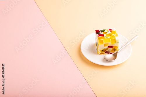 Colored Fruit and milk jelly on pink and orange paper, side view, copy space
