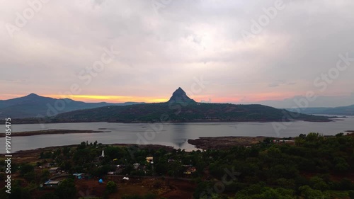 Moving drone shot of Sunset over a lake with dramatic clouds and Mountains in the background shot during monsoon. 4K60fps