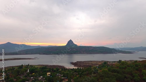Moving drone shot of Sunset over a lake with dramatic clouds and Mountains in the background shot during monsoon. 4K60fps