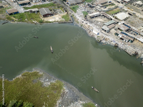 Aerial view of canoes glide on the murky water near akoka, amidst the ramshackle buildings, Oworonshoki, Lagos, Nigeria.