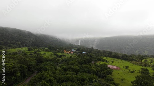 Moving Drone shot of a temple with a waterfall in the background shot in the mountians of India. 4K60fps