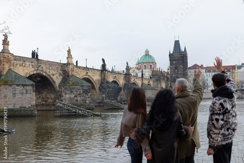 Fotografie Two white family members standing close by river, intimate grandfather and grandson moment with charles bridge backdrop, quiet reflection and soft winter light