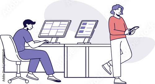 A man sitting at his desk working on computers while a woman stands nearby holding a tablet.