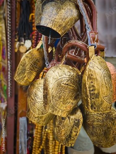 Close up of handmade brass bells with engraved Ladakh motifs at local market in Leh, Himalayas India, authentic cultural and spiritual souvenirs