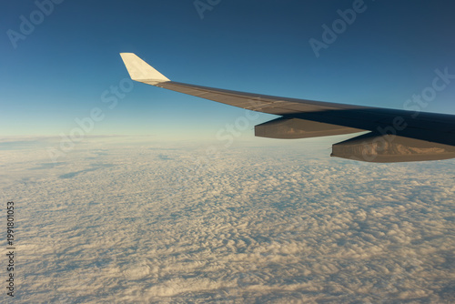 Airplane wing above a sea of clouds at golden hour, capturing travel, freedom, and the journey ahead, ideal for themes of travel, freedom, business trips, and global connectivity, window view