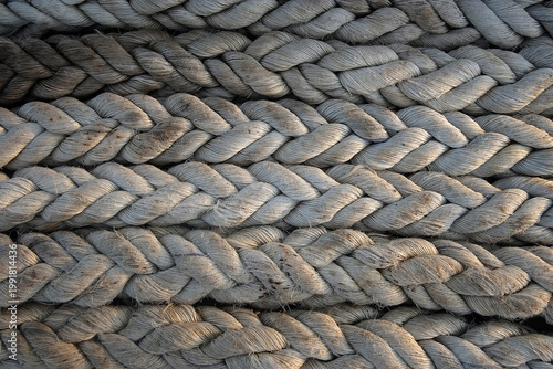 Foto A high-detail, close-up shot of thick, weathered nautical ropes stacked horizontally