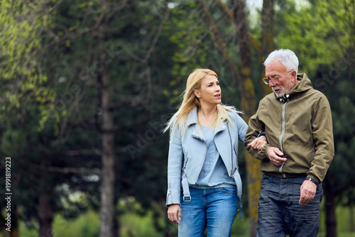 Принти на полотні Younger Woman Supporting Elderly Man Walking Together In Park Showing Care And C