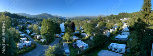 Panoramic View of a Lush Green Campsite with RVs and Tents Under a Clear Blue Sky.