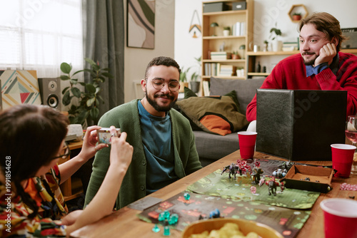 Fotografija Young adult friends playing tabletop roleplaying game, photographing session wit